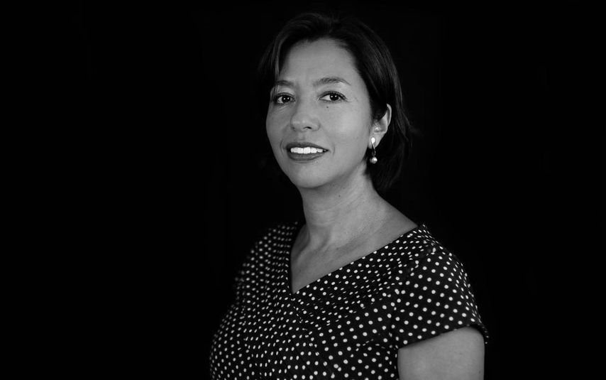 Black and white portrait of a woman wearing a polka dot dress against a black background