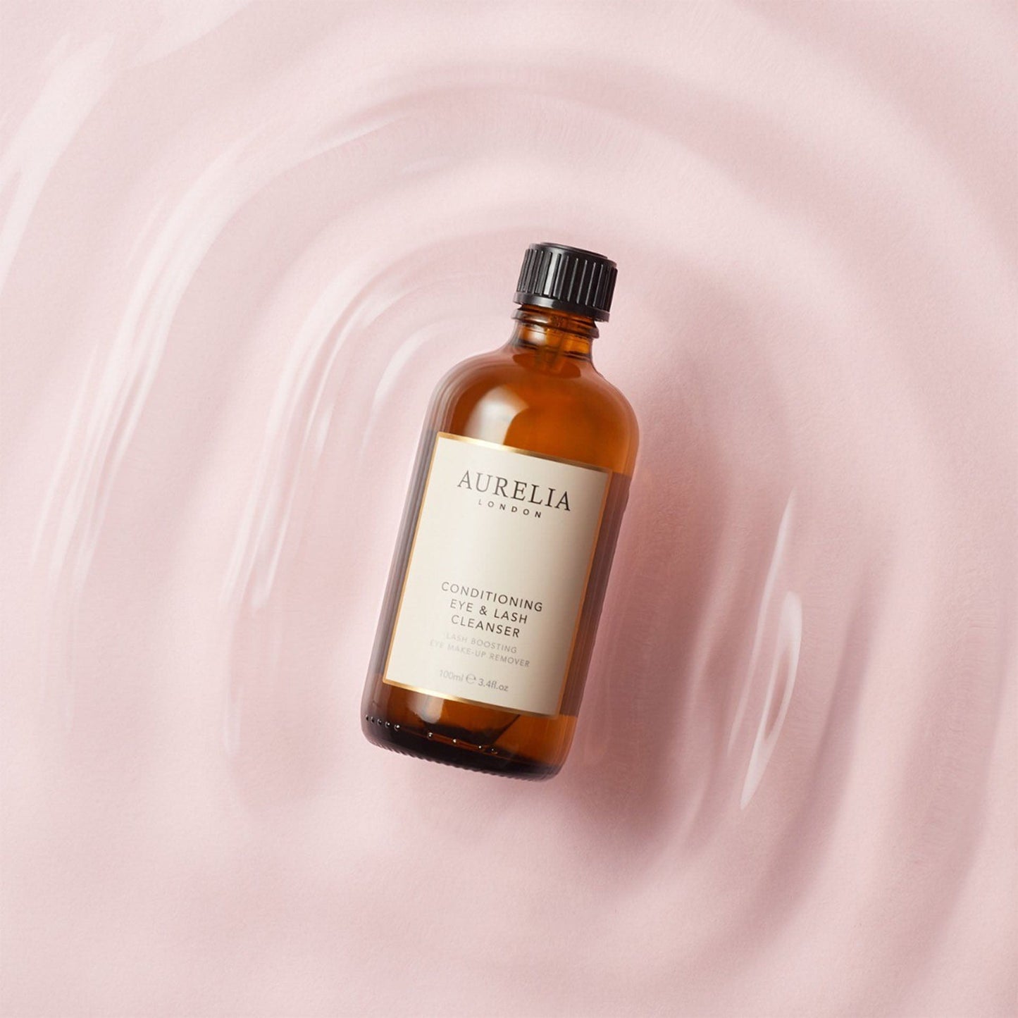 Aurelia eye and lash cleanser bottle on a pink swirling background