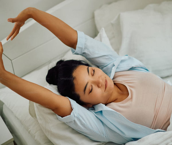 Woman stretching in bed in a bright bedroom
