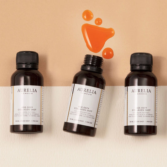 Three Aurelia London age-defying collagen peptide bottles on a beige background with an orange droplet graphic.