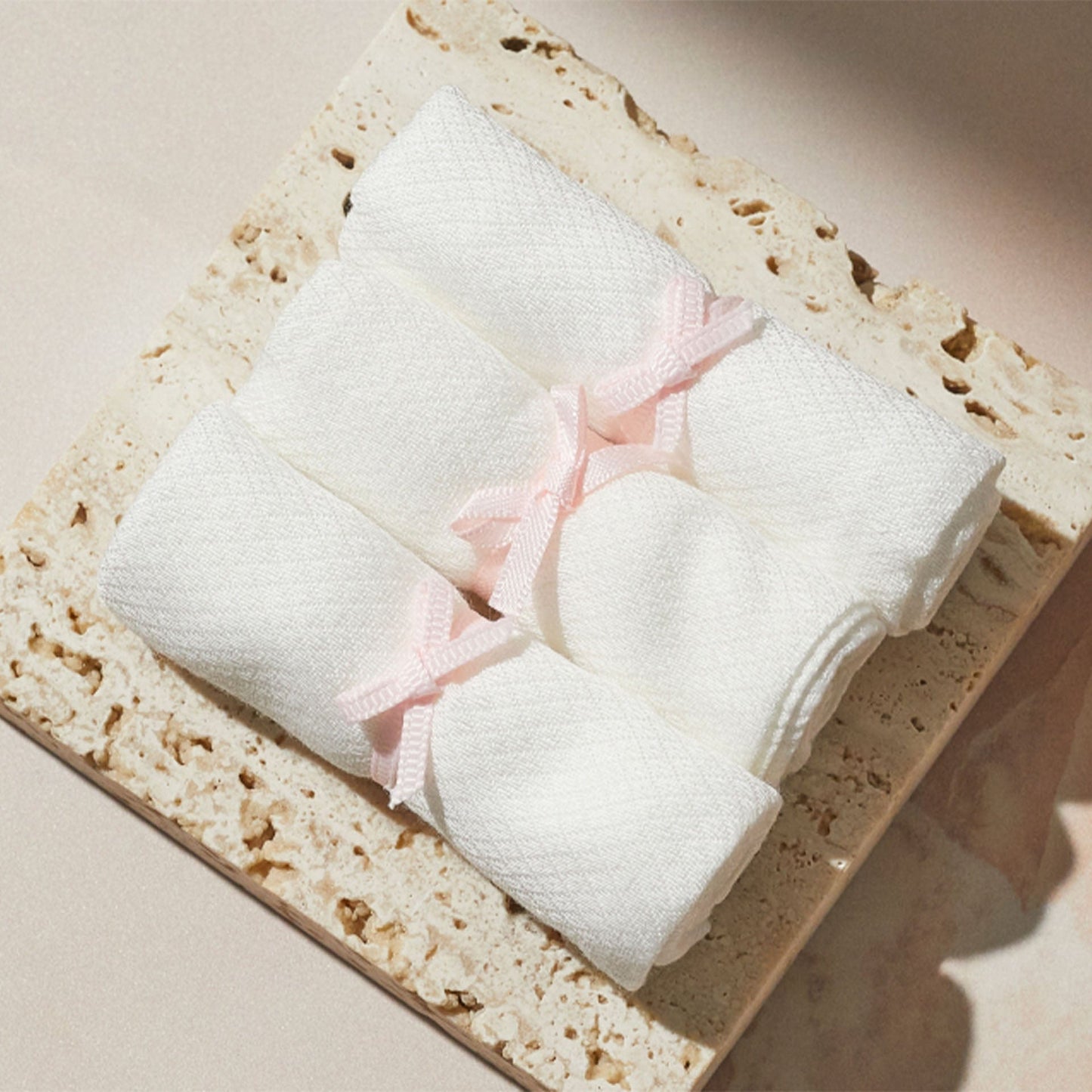 White bamboo muslins with pink bows on a beige stone surface