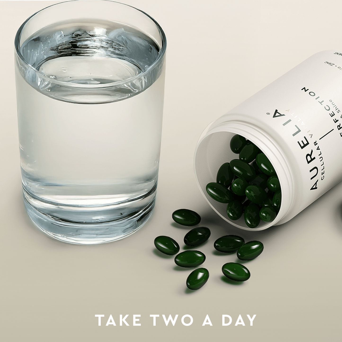 Glass of water next to an open bottle of Aurelia supplements with green capsules on a light background.