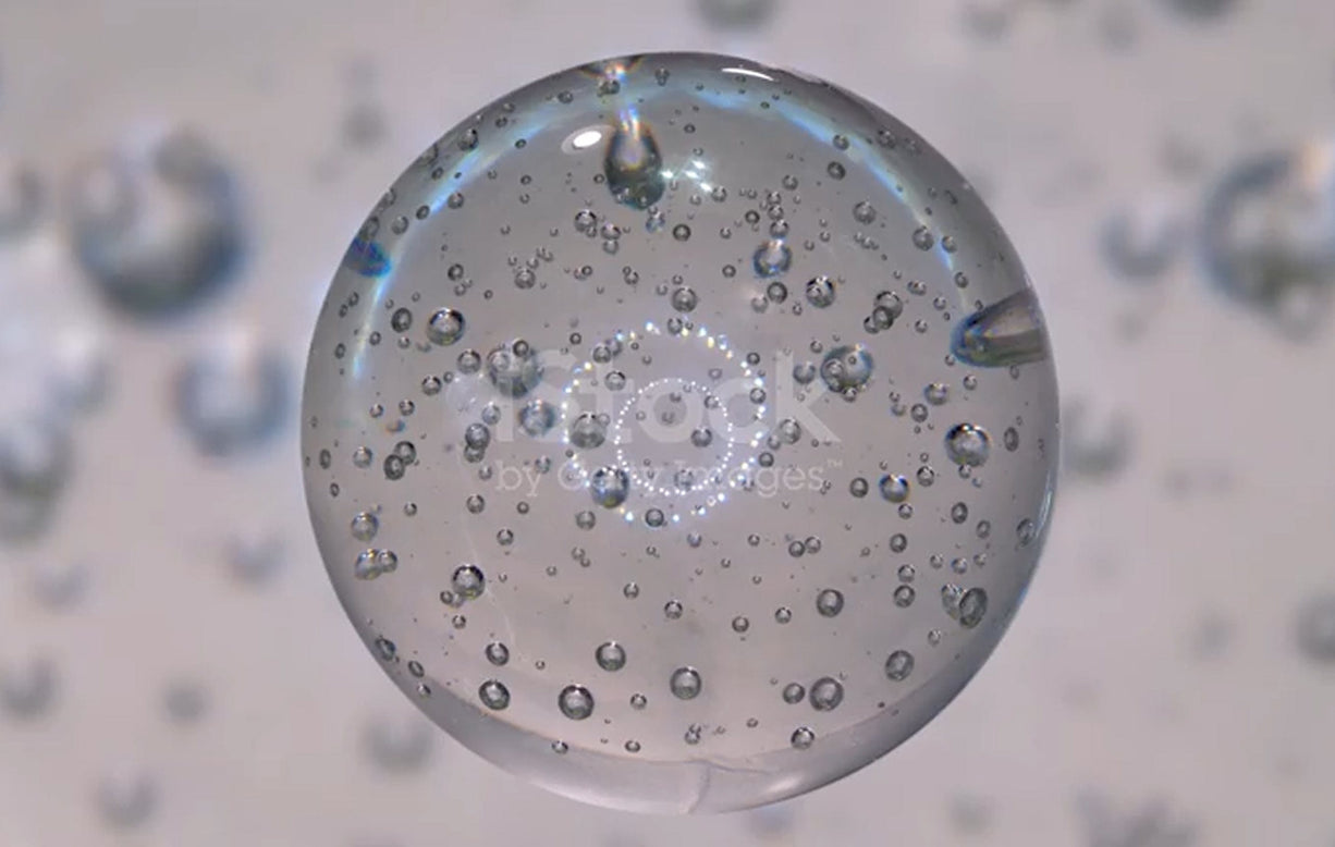 Clear glass sphere with water droplets on a blurred background
