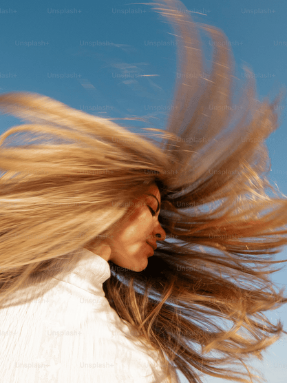 Woman with long blonde hair against a blue sky
